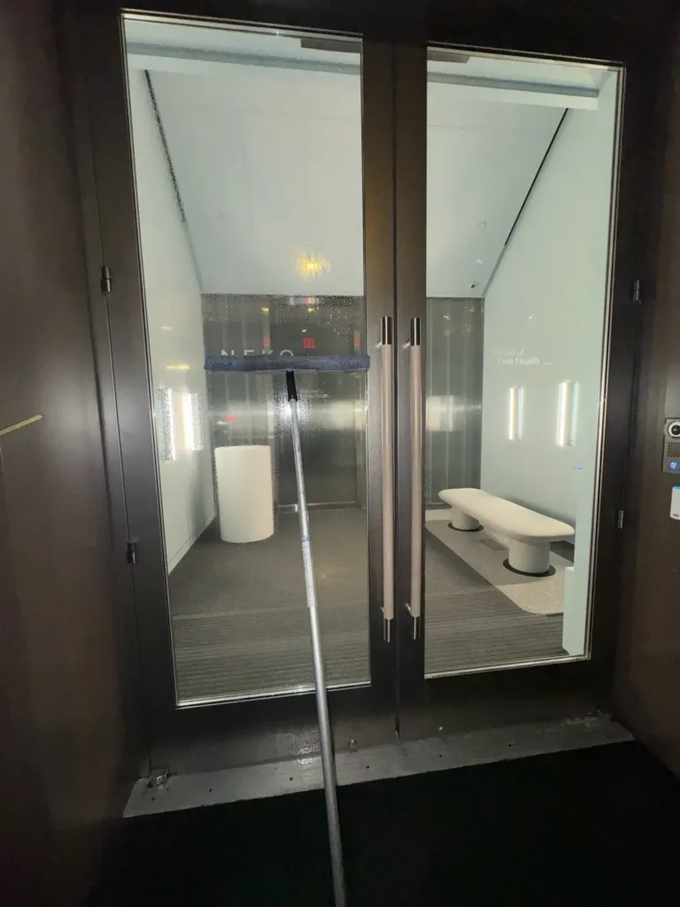 Close view of glass entry doors with a cleaning pole in the foreground.