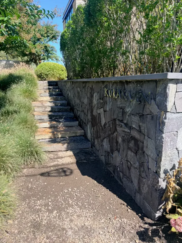 Stone retaining wall and outdoor entry steps beside landscaping.